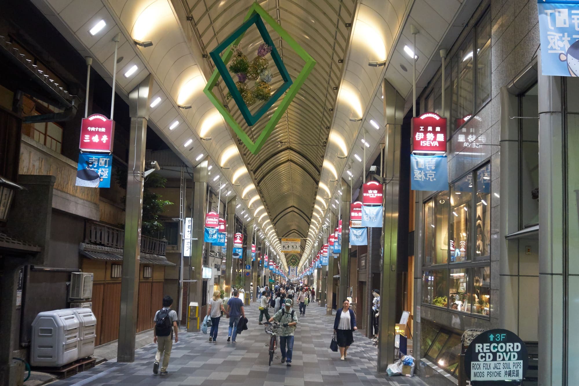 The covered Teramachi shopping arcade, with its arched glass roof, hanging banners and a wooden machiya storefront on the left.
